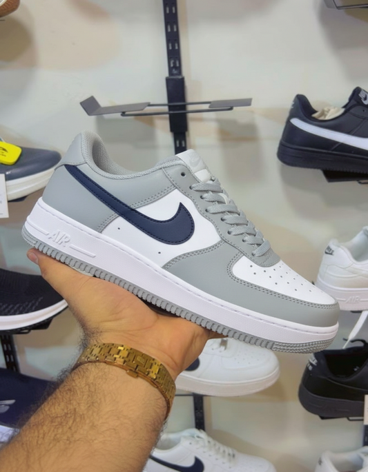 Grey White Navy Nike Air Force 1 held in hand against shoe store shelf
