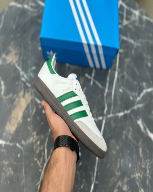 Hand holding Adidas Samba green stripe sneaker