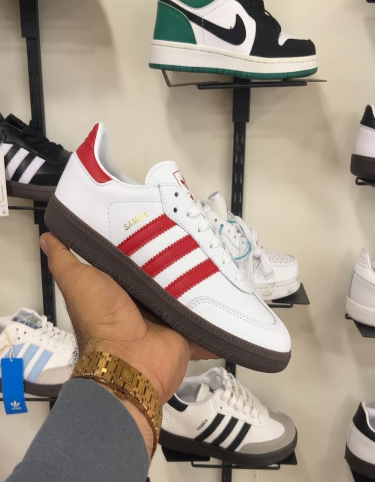 White Red Adidas Samba held in hand against shoe store shelf