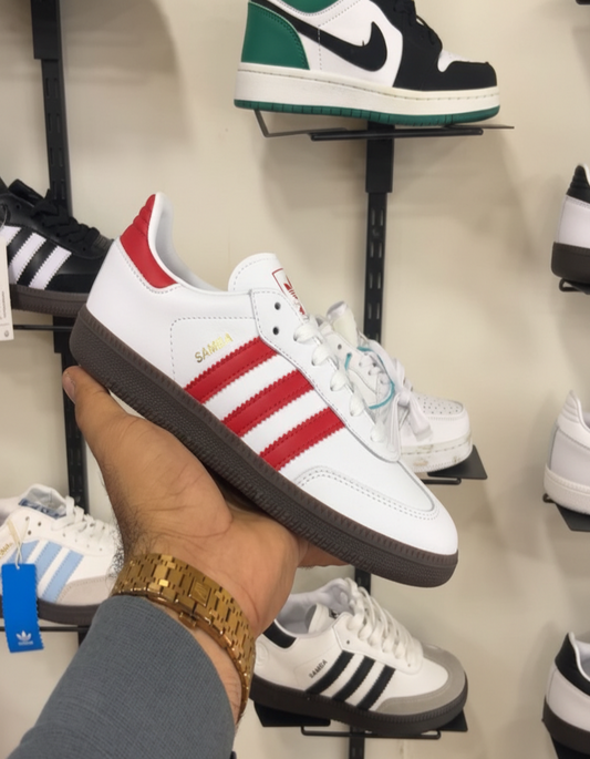 White Red Adidas Samba held in hand against shoe store shelf